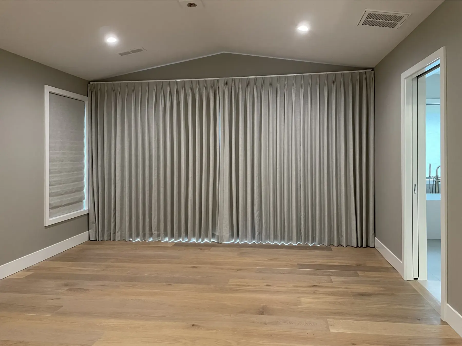 Motorized blackout drapery covering a sliding glass door in a remodeled Redmond primary bedroom