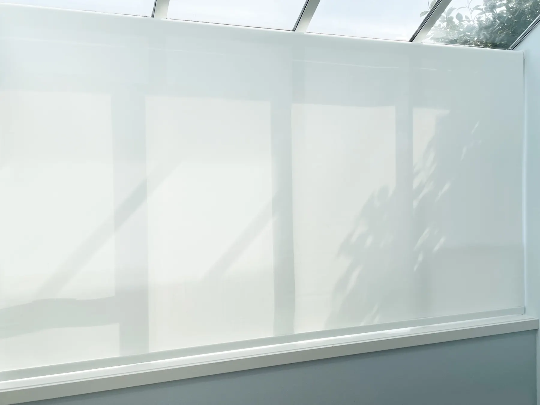 Motorized solar shades across a wide solarium window for heat control and filtered light in a Sammamish nook